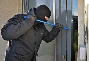 burglar with crowbar breaking into building